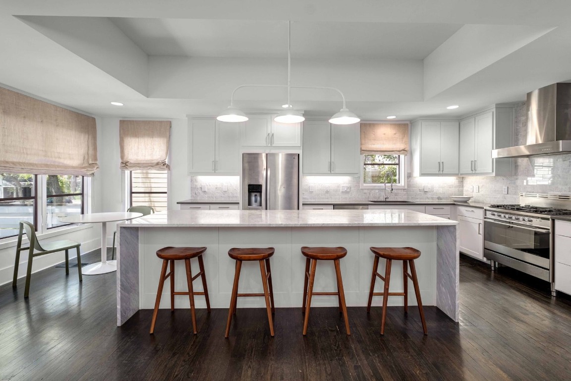 a kitchen with stainless steel appliances granite countertop a kitchen island and chairs in it