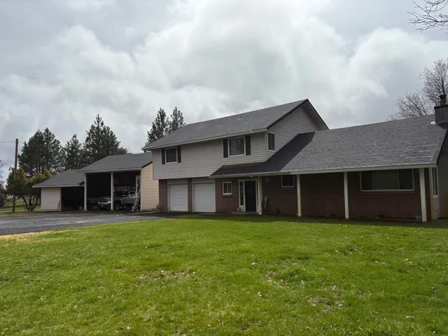a view of a house with a yard and large trees