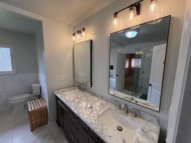 a bathroom with a granite countertop sink a mirror and a shower