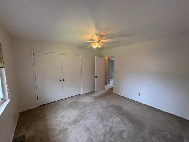 an empty room with a window and a fan