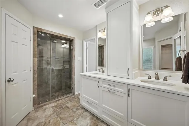 a bathroom with a double vanity sink mirror and shower