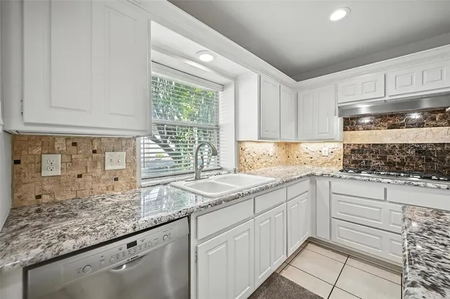 a kitchen with granite countertop white cabinets and window