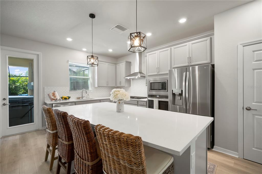 5636 Silver Sun Drive Apollo Beach, FL 33572 - Photo 26 of 61 a kitchen with stainless steel appliances granite countertop a kitchen island a stove a refrigerator a sink a dining table and chairs with wooden floor