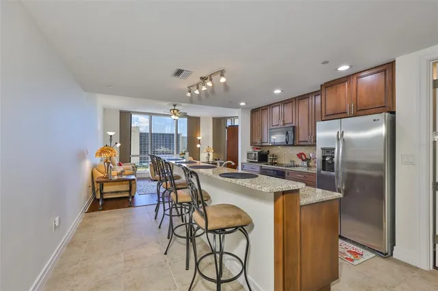 a kitchen with stainless steel appliances kitchen island granite countertop a refrigerator and a stove top oven