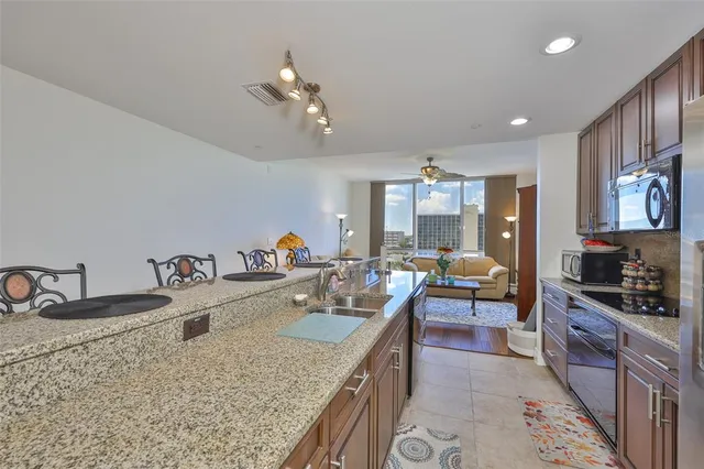 a large kitchen with granite countertop a sink a stove and cabinets