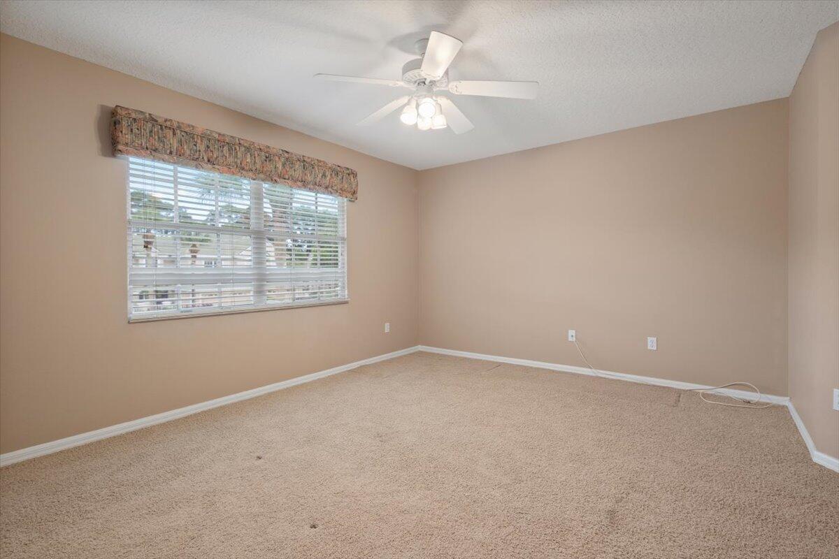 1634 Southwest Harbour Isles Circle, Unit 89 Port St. Lucie, FL 34986 - Photo 47 of 71 an empty room with a chandelier fan and windows
