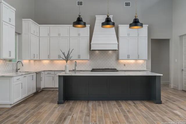 a kitchen with stainless steel appliances granite countertop a sink and wooden floor