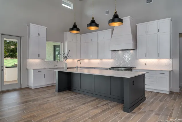 a kitchen with granite countertop a sink cabinets and wooden floor
