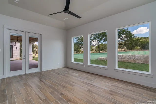 a view of an empty room with wooden floor and a window