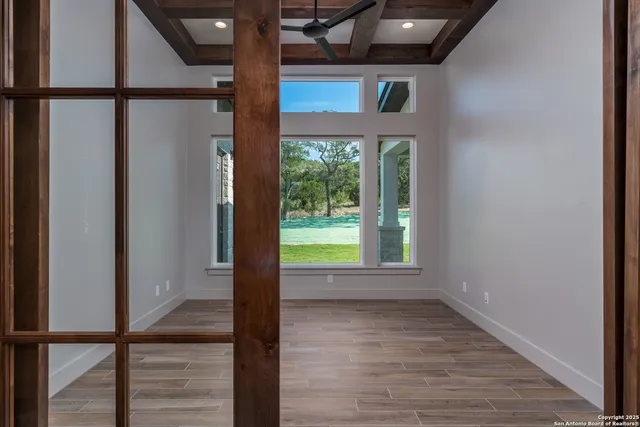 a view of an empty room with wooden floor and a window