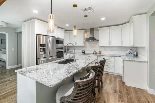 a kitchen with granite countertop kitchen island stainless steel appliances a stove a sink a refrigerator a center island and cabinets