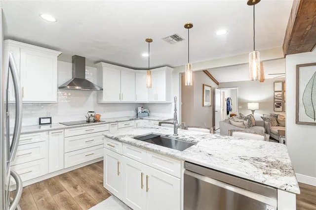 a kitchen with stainless steel appliances granite countertop a sink a stove and cabinets