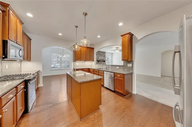 a kitchen with stainless steel appliances granite countertop a sink a granite counter tops and a view of living room