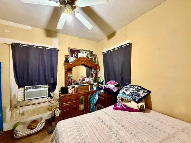 a bedroom with a bed and a dresser with wooden floor