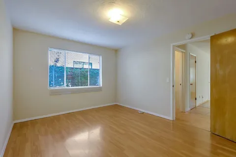 a view of an empty room with window and wooden floor