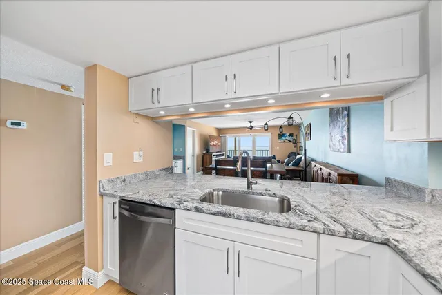 a kitchen with granite countertop a refrigerator a stove and wooden floor