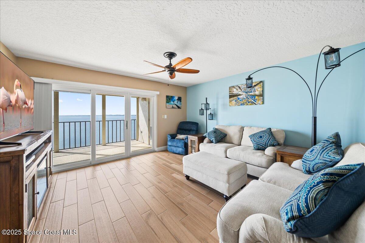 3220 River Villa Way, Unit 151 Melbourne Beach, FL 32951 - Photo 7 of 51 a living room with furniture two large windows and a flat screen tv