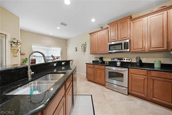 a kitchen with granite countertop a sink stove and microwave