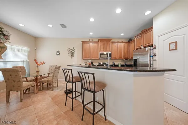 a kitchen with stainless steel appliances granite countertop a refrigerator a stove a sink and a dining table with wooden cabinets
