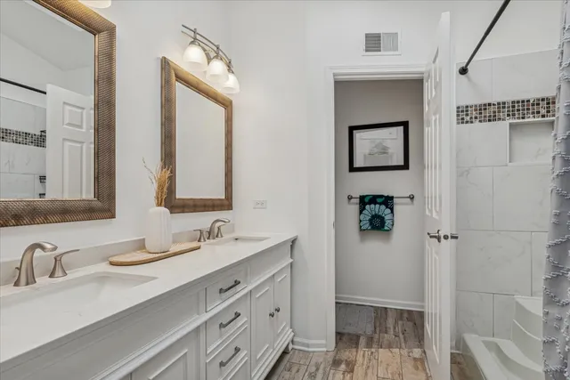 a bathroom with double vanity sink a mirror and a shower