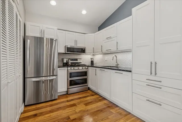 a kitchen with granite countertop a refrigerator stove and wooden cabinets