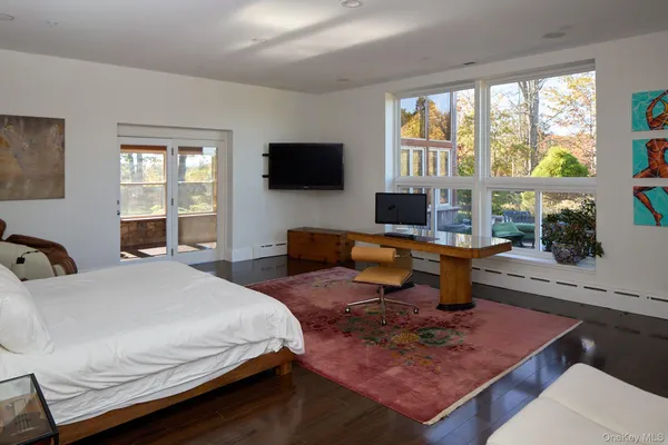a bedroom with a bed a large window and a flat screen television