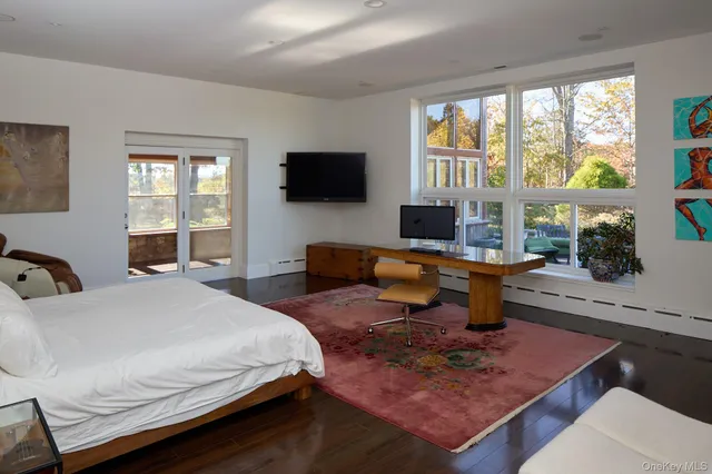 a bedroom with a bed a large window and a flat screen television