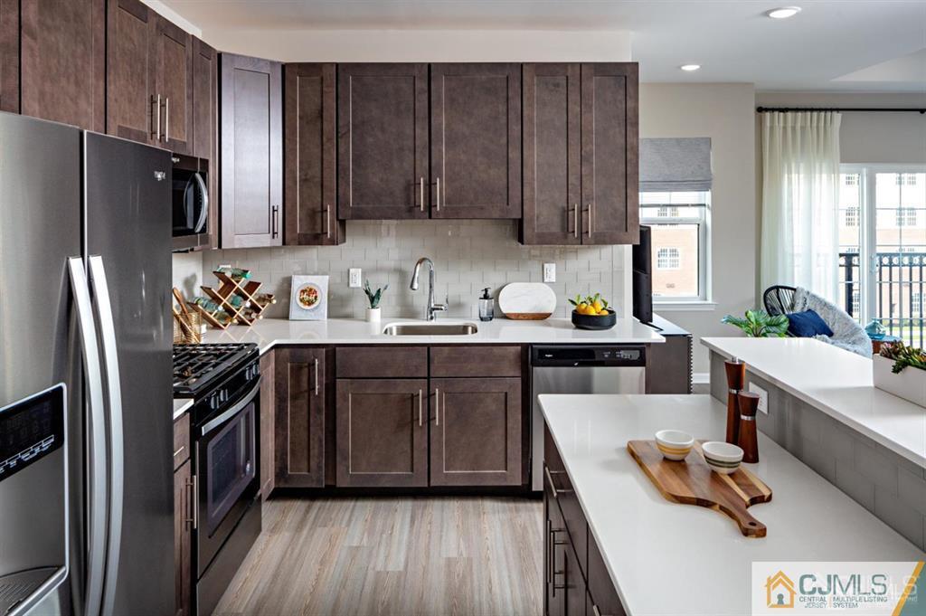 a kitchen with stainless steel appliances a sink a stove a refrigerator cabinets and wooden floor