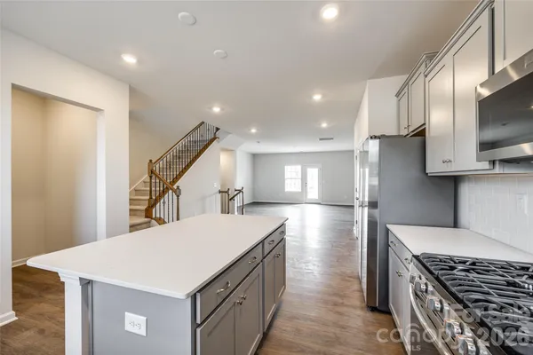 a kitchen with stainless steel appliances a sink a stove a refrigerator cabinets and living room view