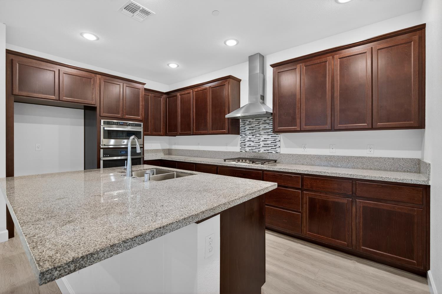 2340 Bellows Way Lodi, CA 95242 - Photo 19 of 42 a kitchen with kitchen island granite countertop wooden cabinets a sink and dishwasher