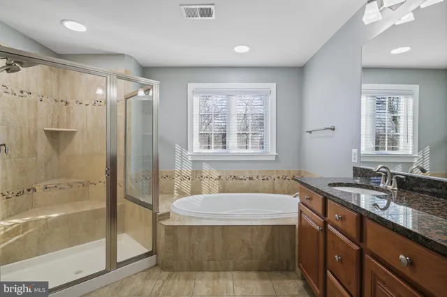 a bathroom with a granite countertop tub sink shower and mirror