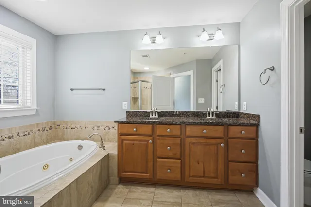 a spacious bathroom with a tub sink and mirror