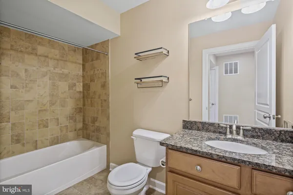 a bathroom with a granite countertop sink a toilet and bathtub
