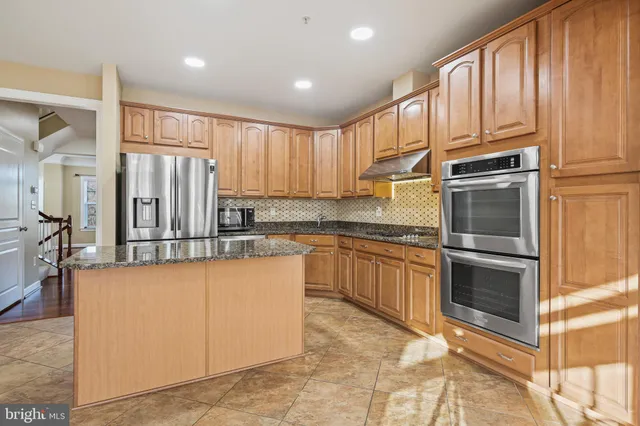 a kitchen with granite countertop a refrigerator stove top oven and cabinets