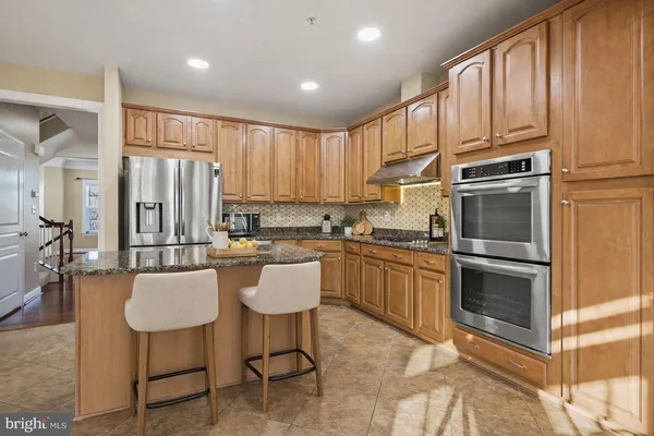 a kitchen with a refrigerator cabinets and chairs