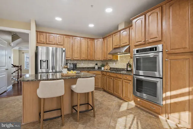 a kitchen with a refrigerator cabinets and chairs