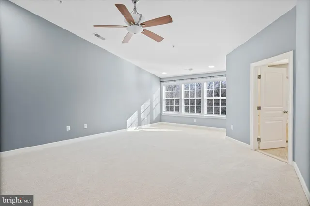 an empty room with windows and ceiling fan