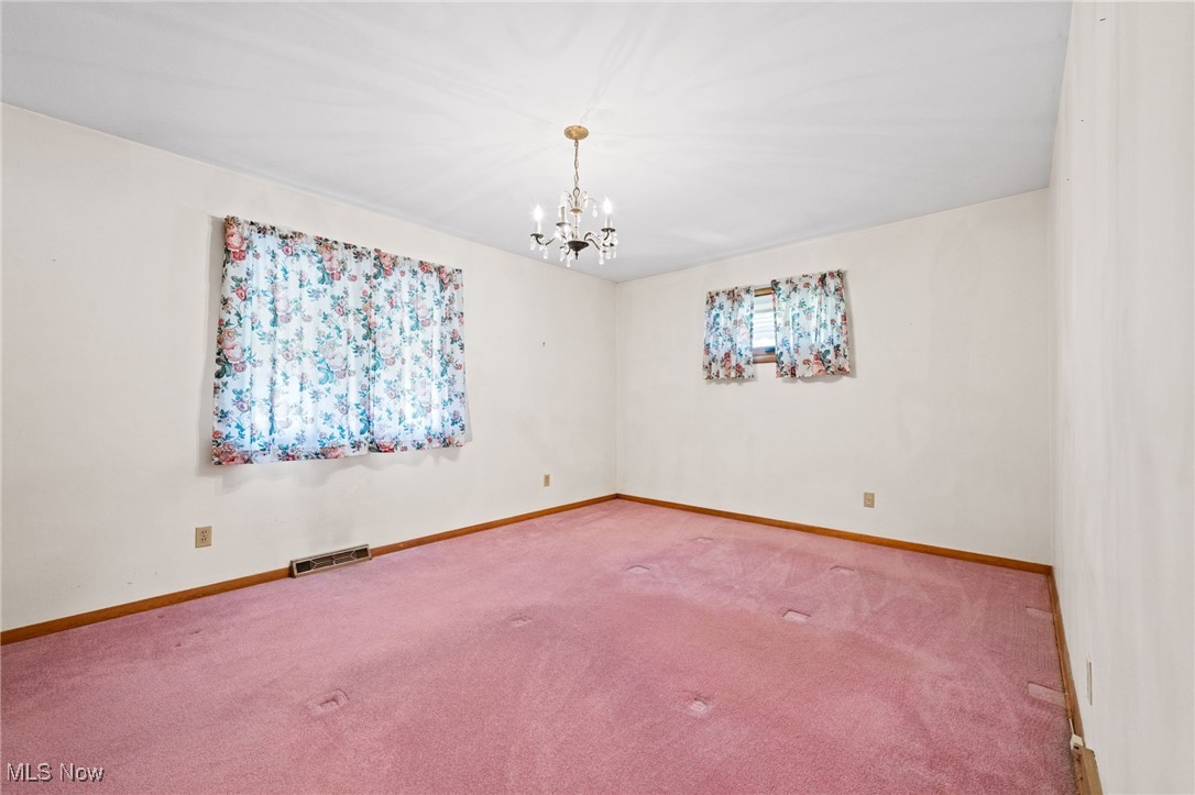 586 Bishop Road Cleveland, OH 44143 - Photo 14 of 24 Spare room with carpet floors, baseboards, visible vents, and a chandelier