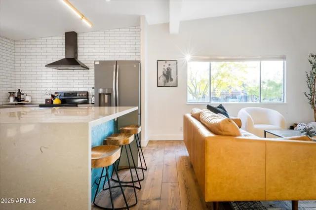 a living room with stainless steel appliances furniture a large window and a wooden floor