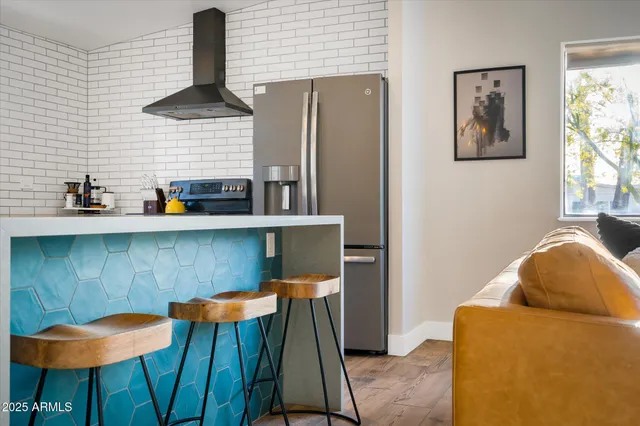 a kitchen with stainless steel appliances kitchen island a table chairs in it and wooden floors