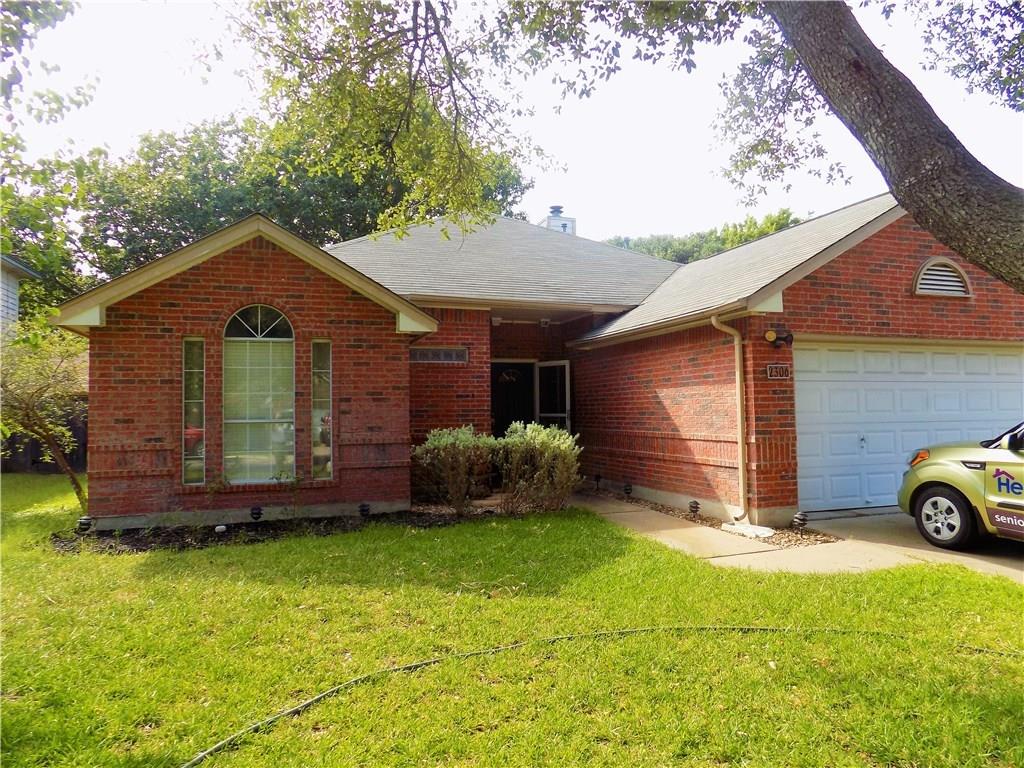 Brick exterior featuring an arched window, two-car garage, and established landscaping