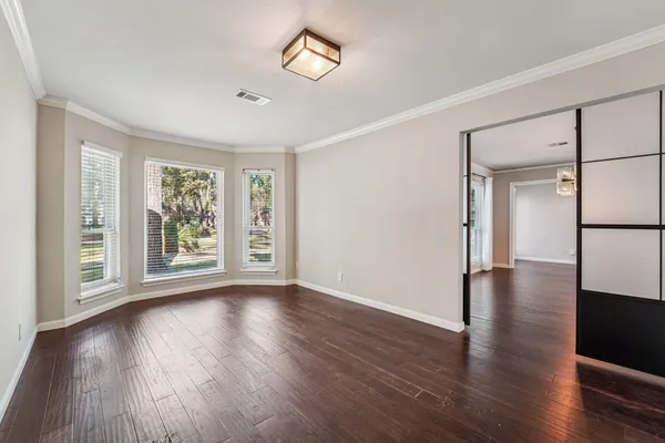 a view of an empty room with wooden floor and a window