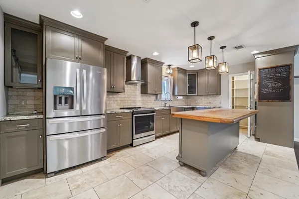 a kitchen with granite countertop a refrigerator oven a sink and cabinets