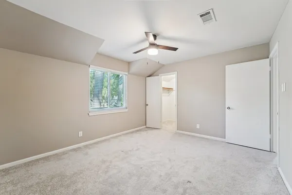 an empty room with windows and fan