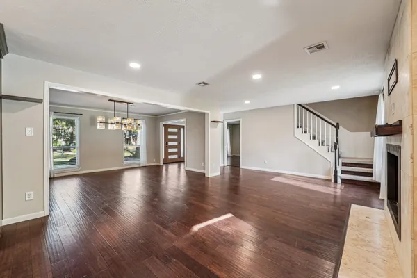 a view of an empty room with a window and wooden floor