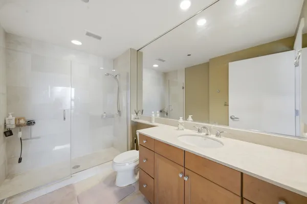 a bathroom with a shower sink vanity mirror and toilet
