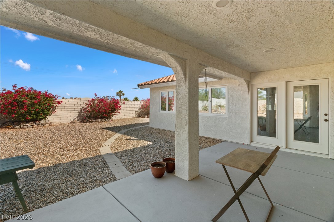 2055 Cholla Way Laughlin, NV 89029 - Photo 50 of 87 A spacious covered patio invites relaxation, overlooking a xeriscaped yard framed by a block wall and vibrant bougainvillea.