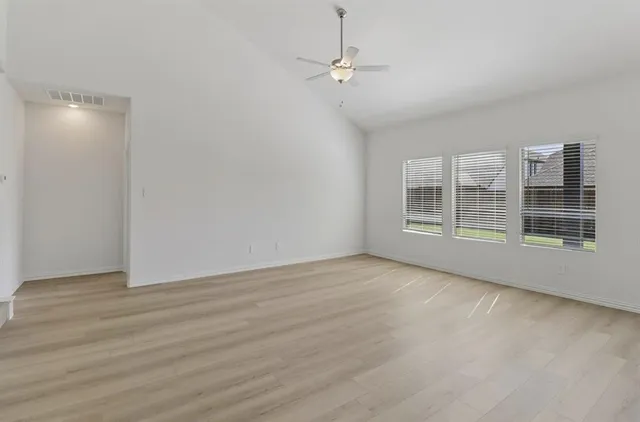 a view of an empty room with a window and wooden floor