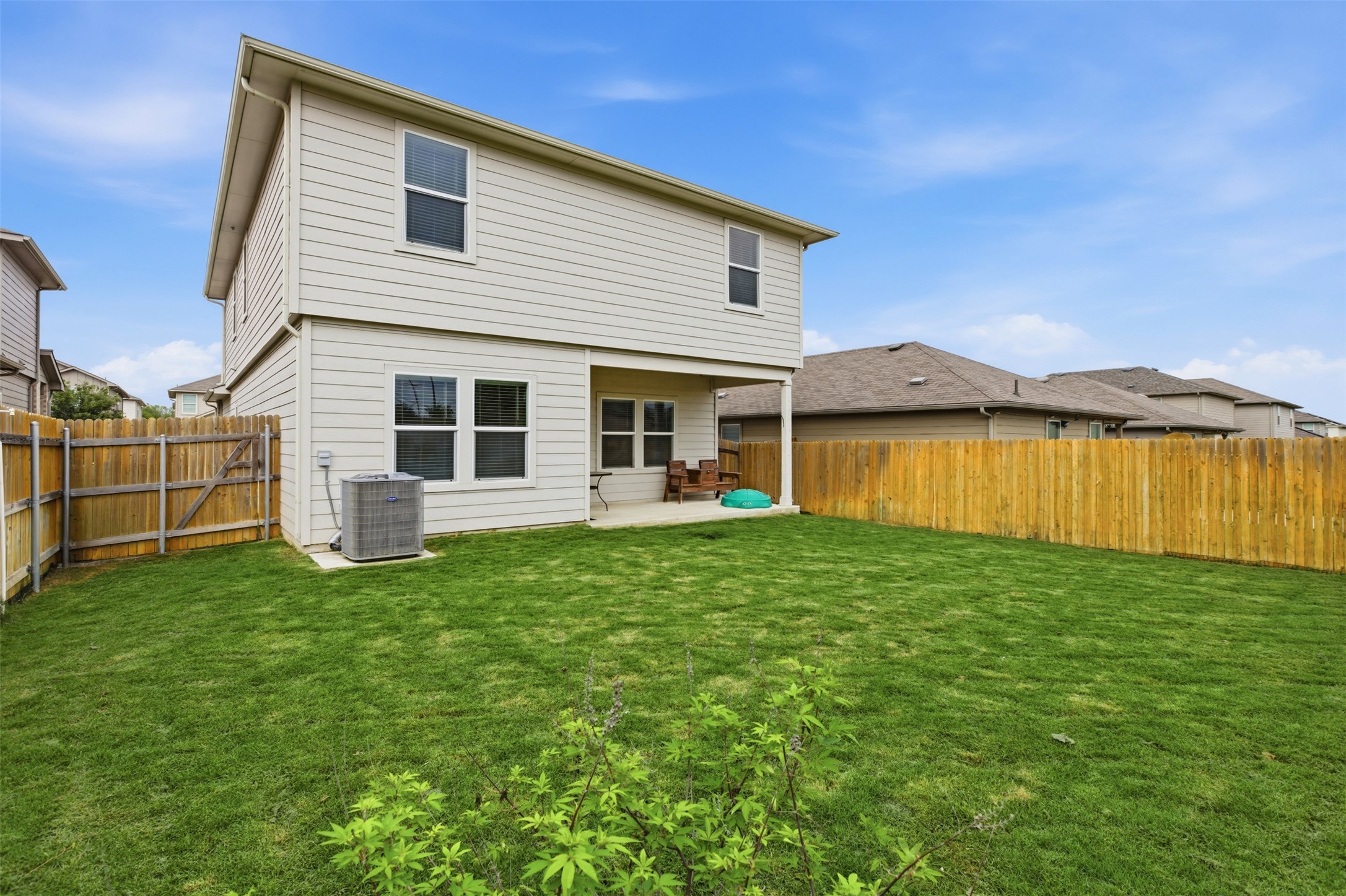19017 Romano Drive Elgin, TX 78621 - Photo 33 of 33 Rear exterior featuring a covered patio, a spacious grass lawn, and a wood privacy fence