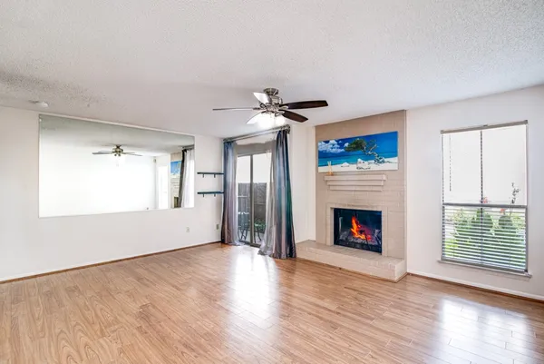 a view of an empty room with wooden floor fireplace and a window